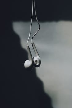 Artistic shot of wired earphones hanging with shadows, illustrating modern minimalist tech design.