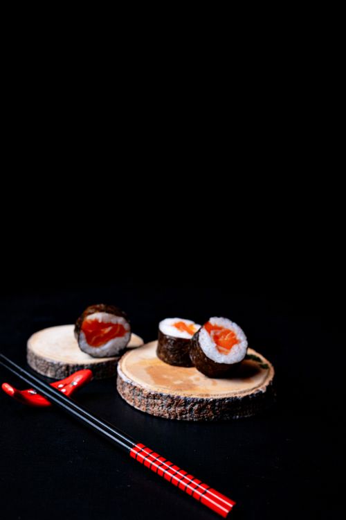 Free Artistic sushi presentation with chopsticks and wood platters, set against a dark background. Stock Photo
