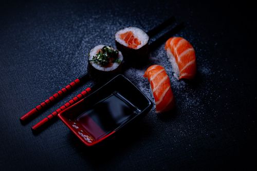 Free Artistic presentation of salmon sushi with soy sauce and chopsticks on a dark background. Stock Photo