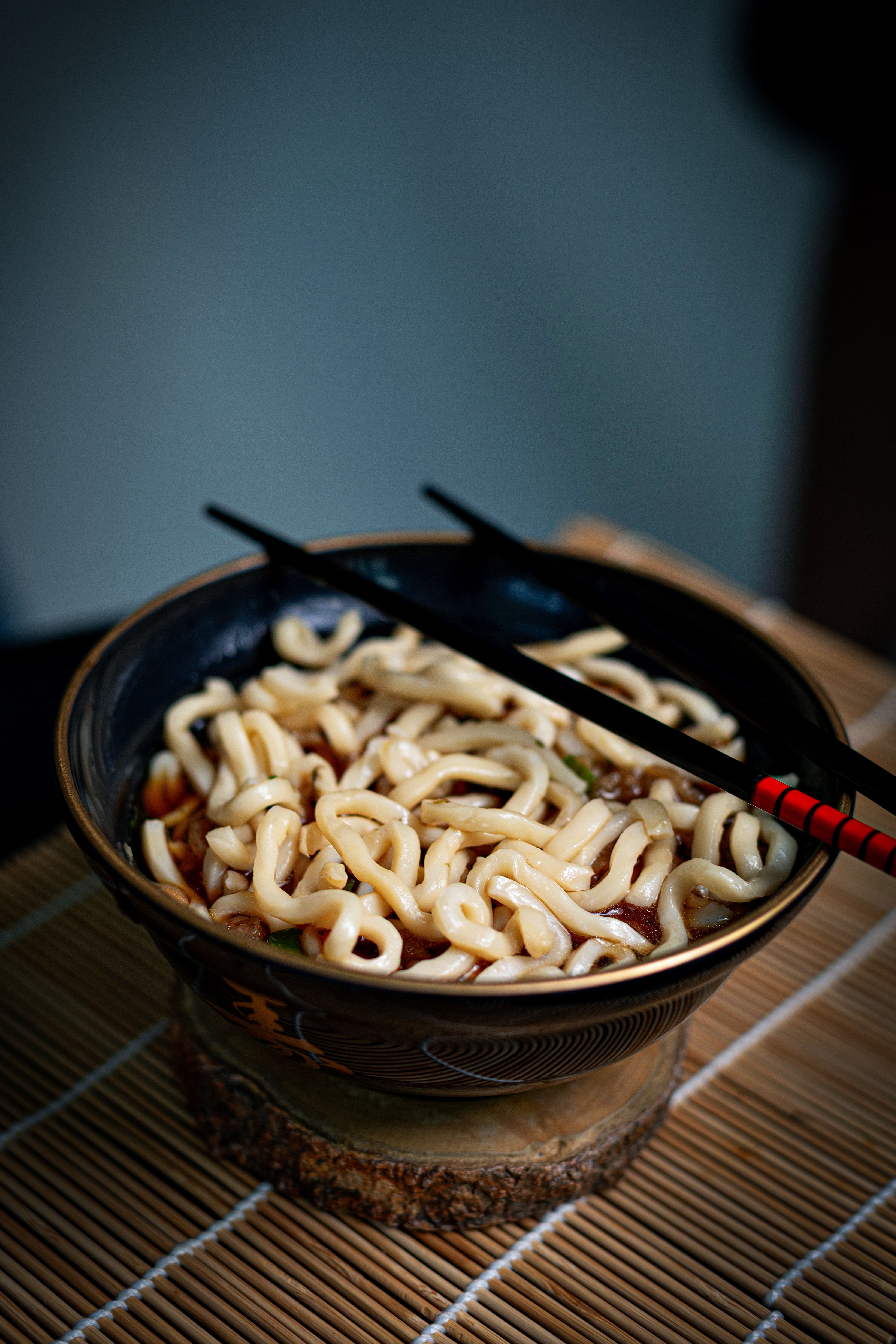 A beautifully presented bowl of udon noodles with chopsticks, perfect for Asian cuisine lovers.