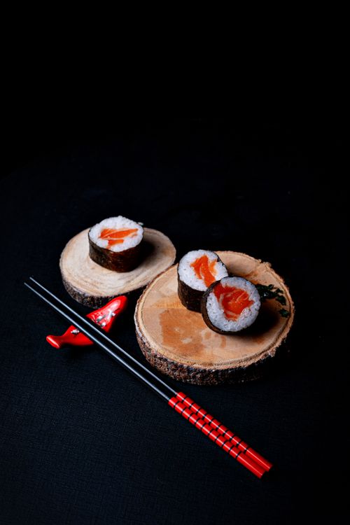 Free Sushi rolls served on wooden slices with red chopsticks on a dark background. Stock Photo