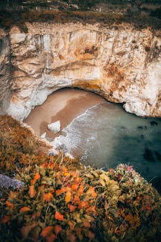 A serene beach cove nestled between dramatic cliffs, perfect for travel and nature enthusiasts.