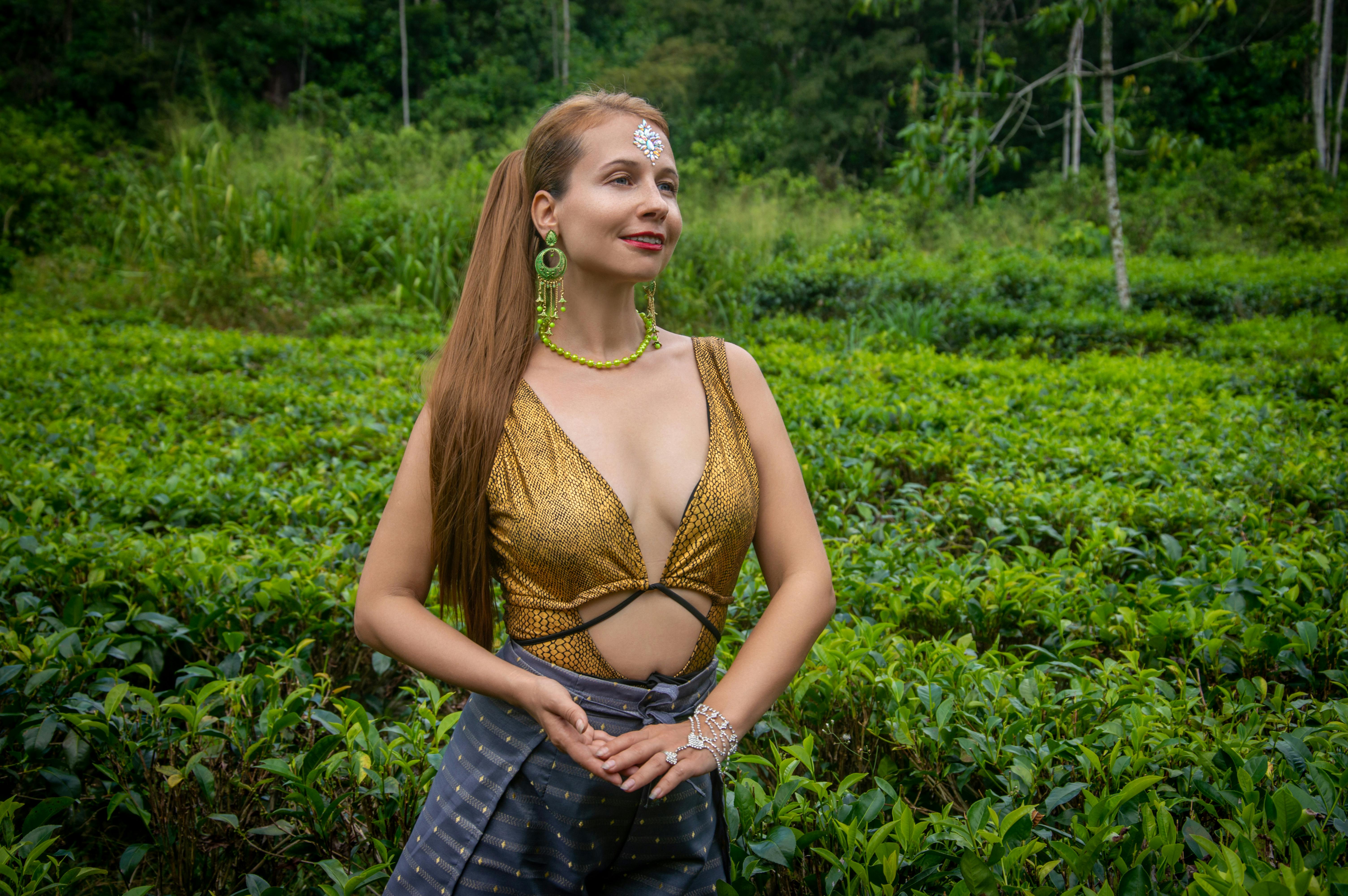 Gratis Mujer elegante con top brillante y joyas en un exuberante campo verde. Foto de stock