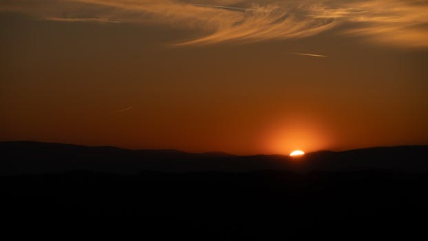 A breathtaking sunset with silhouetted mountains and a calming sky, perfect for serene backgrounds.