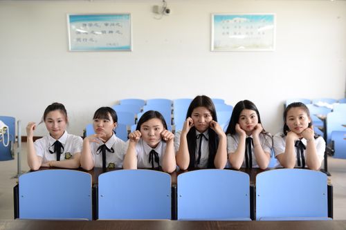Free Six female students in uniform sitting at a desk in a classroom setting. Stock Photo