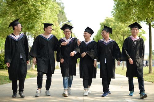 Free A group of cheerful graduates in caps and gowns walking outside, celebrating their achievement. Stock Photo
