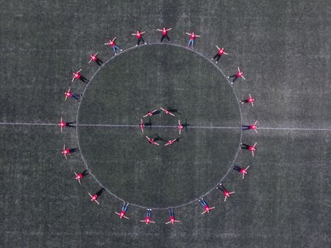 Aerial photo capturing people in circular formation on a grassy field, showcasing coordination and unity from above.