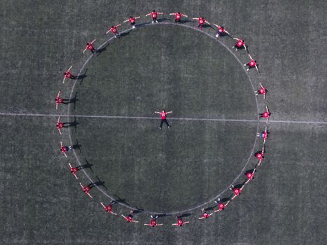 Aerial shot of a sports team forming a perfect circle on a field, symbolizing teamwork.
