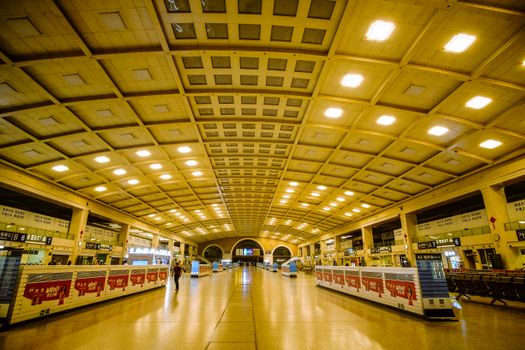 Expansive train station interior with arched ceiling and illuminated lighting.