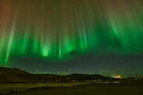 Free Breathtaking view of Northern Lights dancing over wintery Icelandic terrain at night. Stock Photo