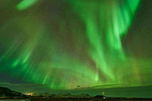 Free Vivid aurora borealis lights up the night sky over a snowy Icelandic landscape. Stock Photo