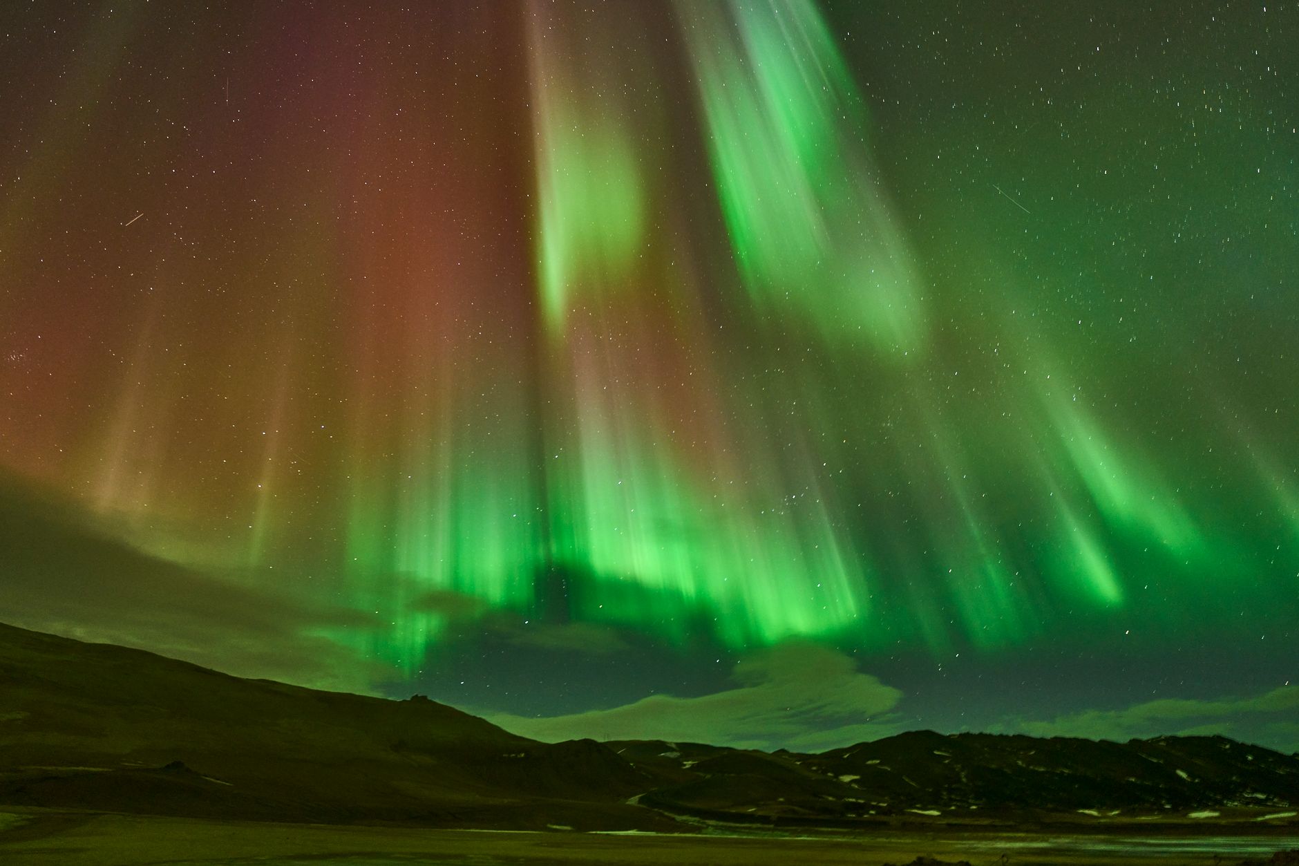 Northern lights dancing over Iceland landscape at night