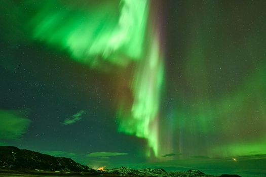 Breathtaking view of the northern lights illuminating the night sky over snowy landscapes in Reykjahlíð, Iceland.