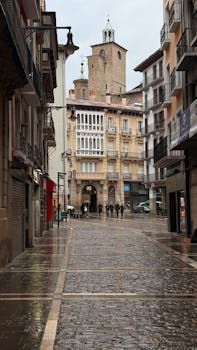 Cobblestone street in Pamplona, Spain, with historic architecture, captured on a rainy day.