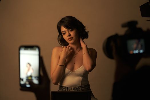 Young woman posing in a studio during a photography session with cameras.