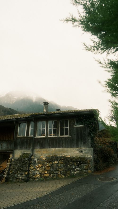 Free A rustic cabin set against foggy mountain landscape, exuding tranquility and nostalgia. Stock Photo