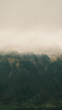A serene mountain landscape with fog rolling over the peaks, creating a mystical atmosphere.