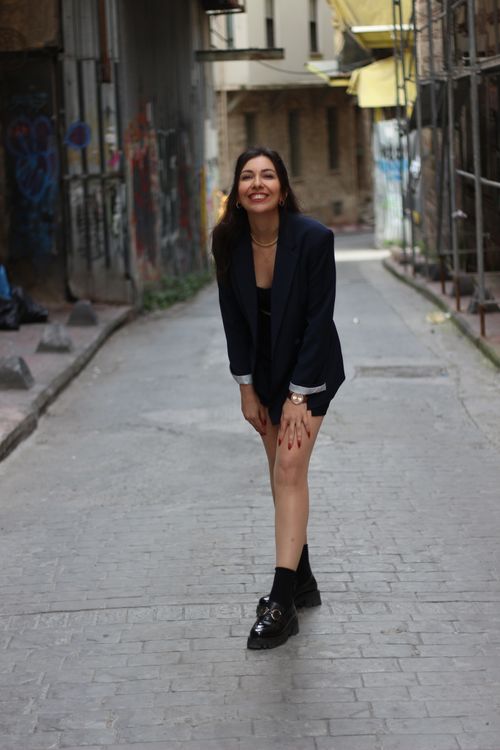 Free A woman in a blazer joyfully poses in a graffiti-covered alley in İstanbul, Türkiye. Stock Photo