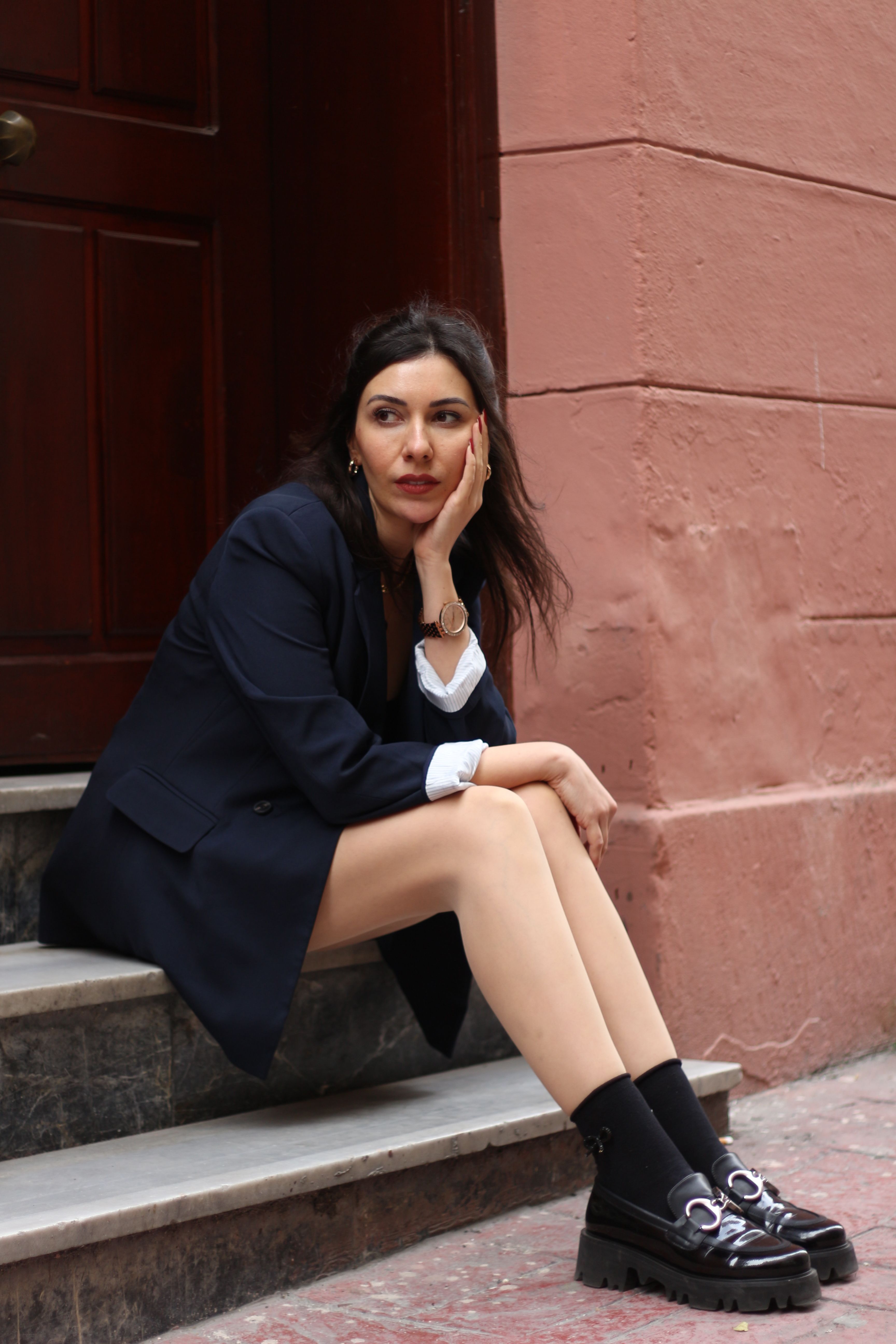Woman in fashionable attire sitting on steps in Istanbul, exuding a modern street style vibe.