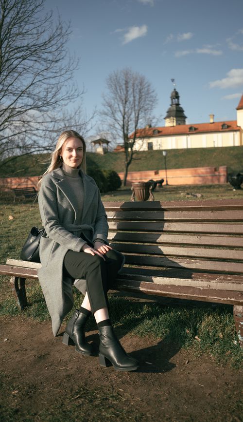 Free A woman enjoys a sunny day on a bench with Niasvizh Castle in the background. Stock Photo