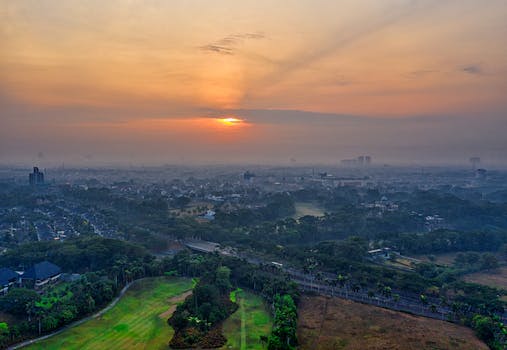 A stunning aerial perspective of Banten, Indonesia at sunrise, showcasing a lush landscape and distant cityscape.