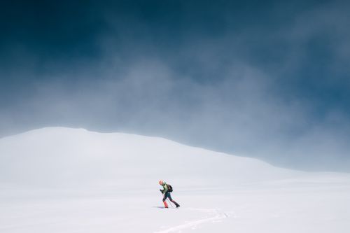 Free A lone skier traverses a vast, snowy landscape under a clear sky. Stock Photo