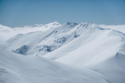 Free Panoramic view of snow-covered mountains under a clear blue sky. Stock Photo