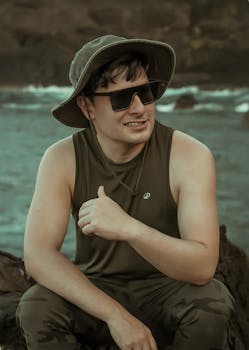 Man in outdoor gear enjoying a moment by the sea, exuding adventure and tranquility.