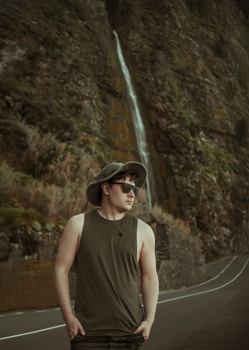 Free Man in nature with waterfall backdrop, embodying adventure and exploration. Stock Photo