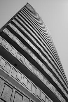 低角度黑白镜头下的现代摩天大楼，展现出大胆的几何线条与建筑结构