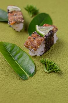 Artistic sushi arrangement featuring lime garnish on a green textured surface.