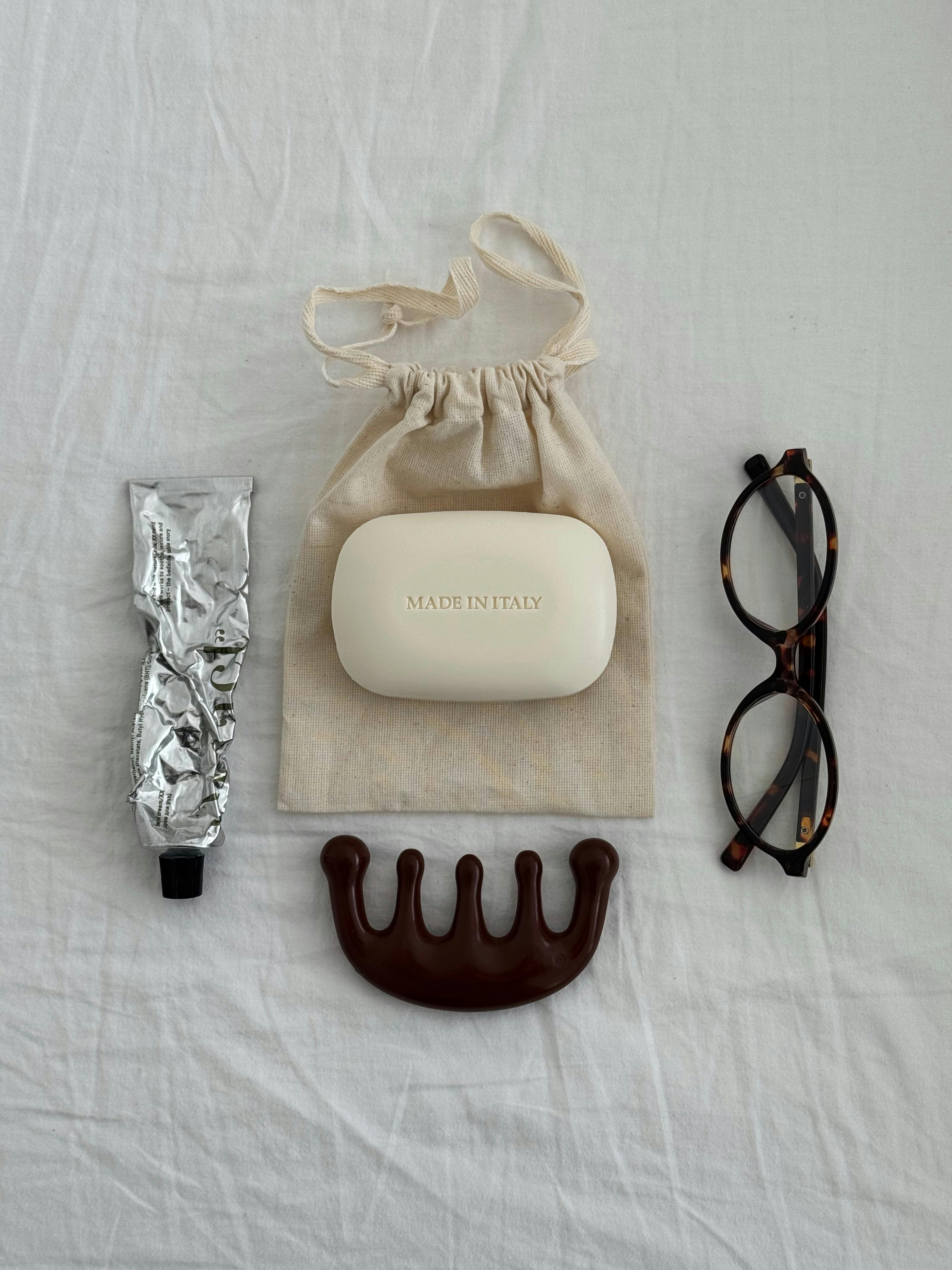 Minimalist flat lay featuring beauty essentials including soap, eyeglasses, and a comb.