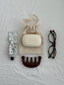 Minimalist flat lay featuring beauty essentials including soap, eyeglasses, and a comb.