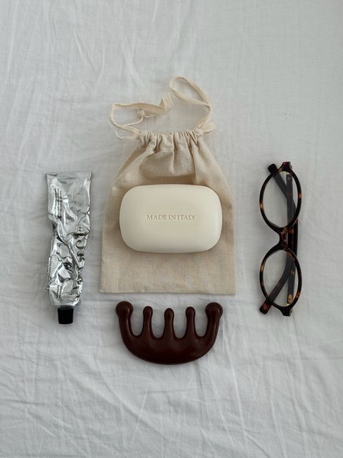Minimalist flat lay featuring beauty essentials including soap, eyeglasses, and a comb.