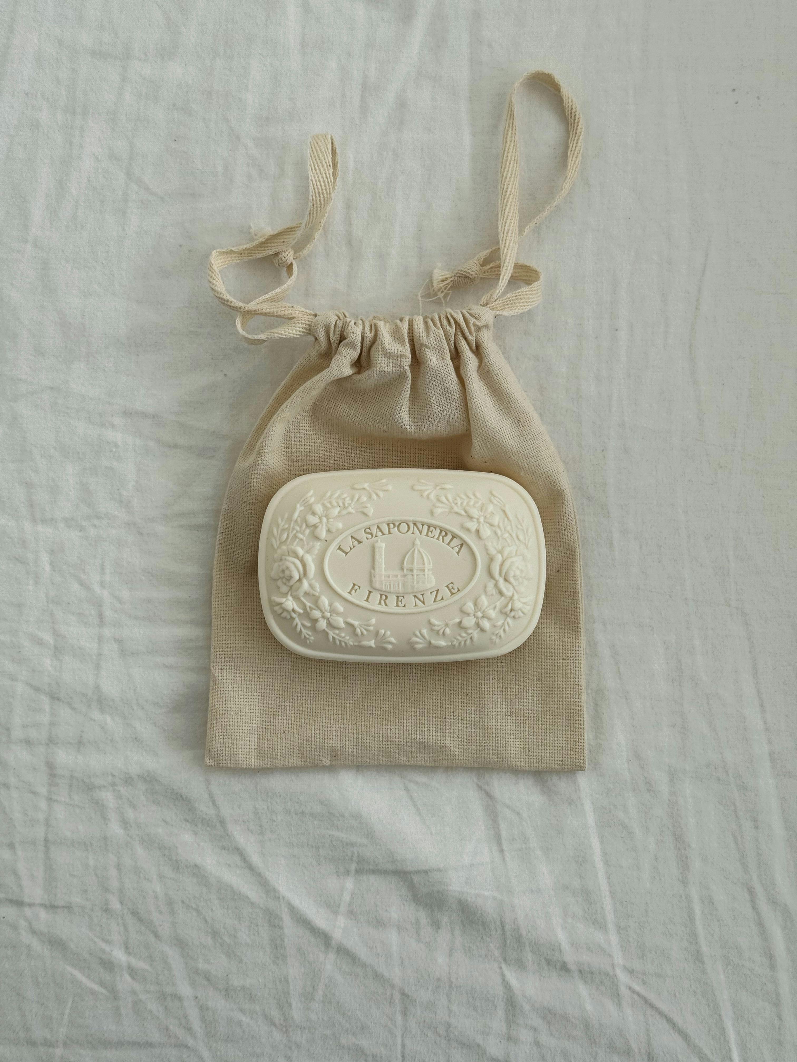White artisanal soap displayed on a natural fabric linen bag.