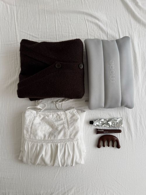 Free Flat lay of clothing, pillow, and accessories on a bed, creating a minimalist aesthetic. Stock Photo