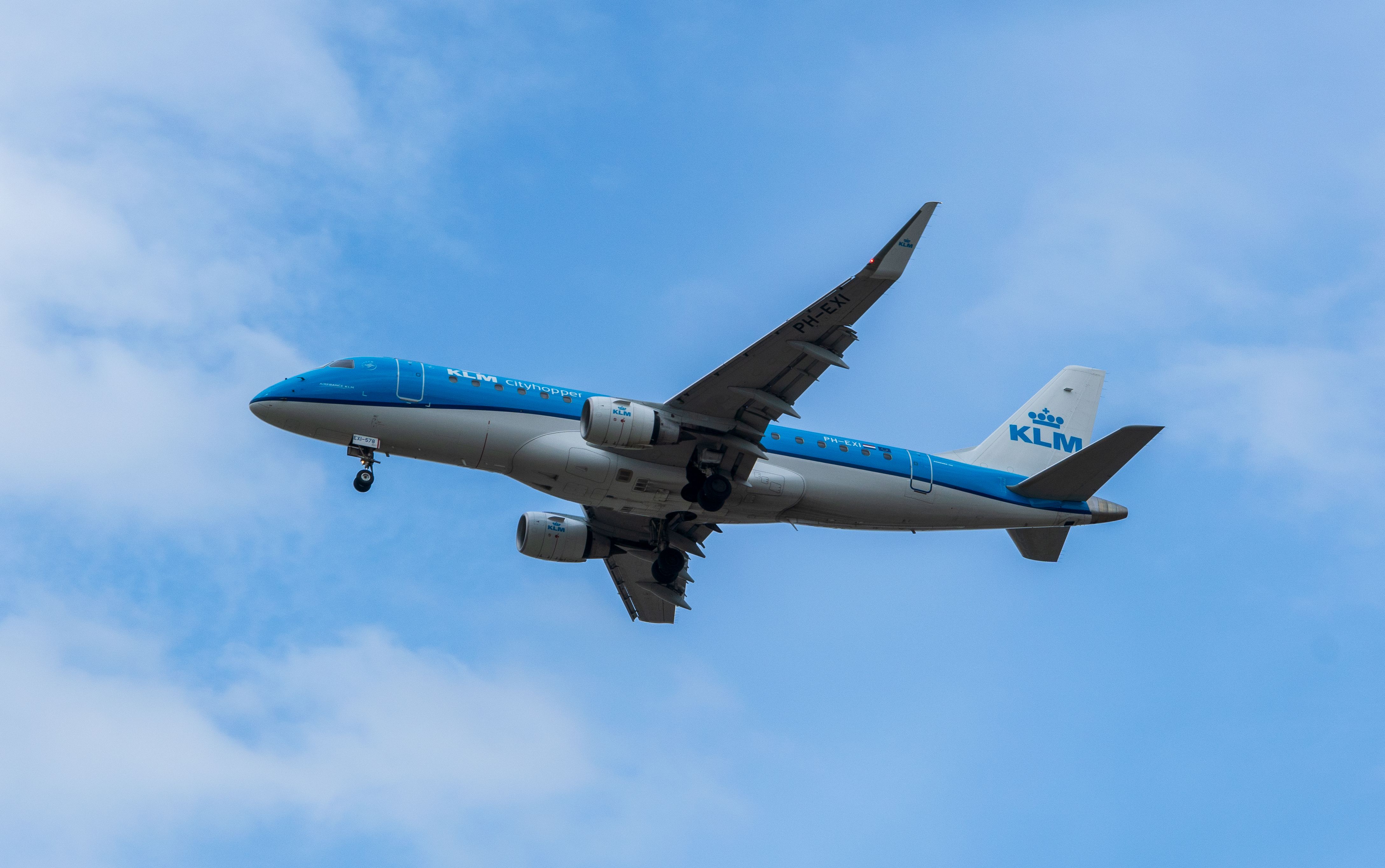 A KLM Cityhopper Embraer 175 aircraft flying against a clear blue sky.