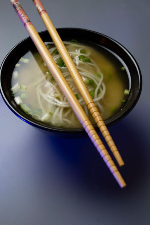 Free Warm Japanese soba noodle soup topped with scallions in a black bowl with chopsticks. Stock Photo