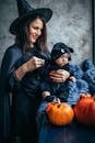 一位快乐的母亲在室内抱着她穿着万圣节服装的孩子，周围摆满了南瓜