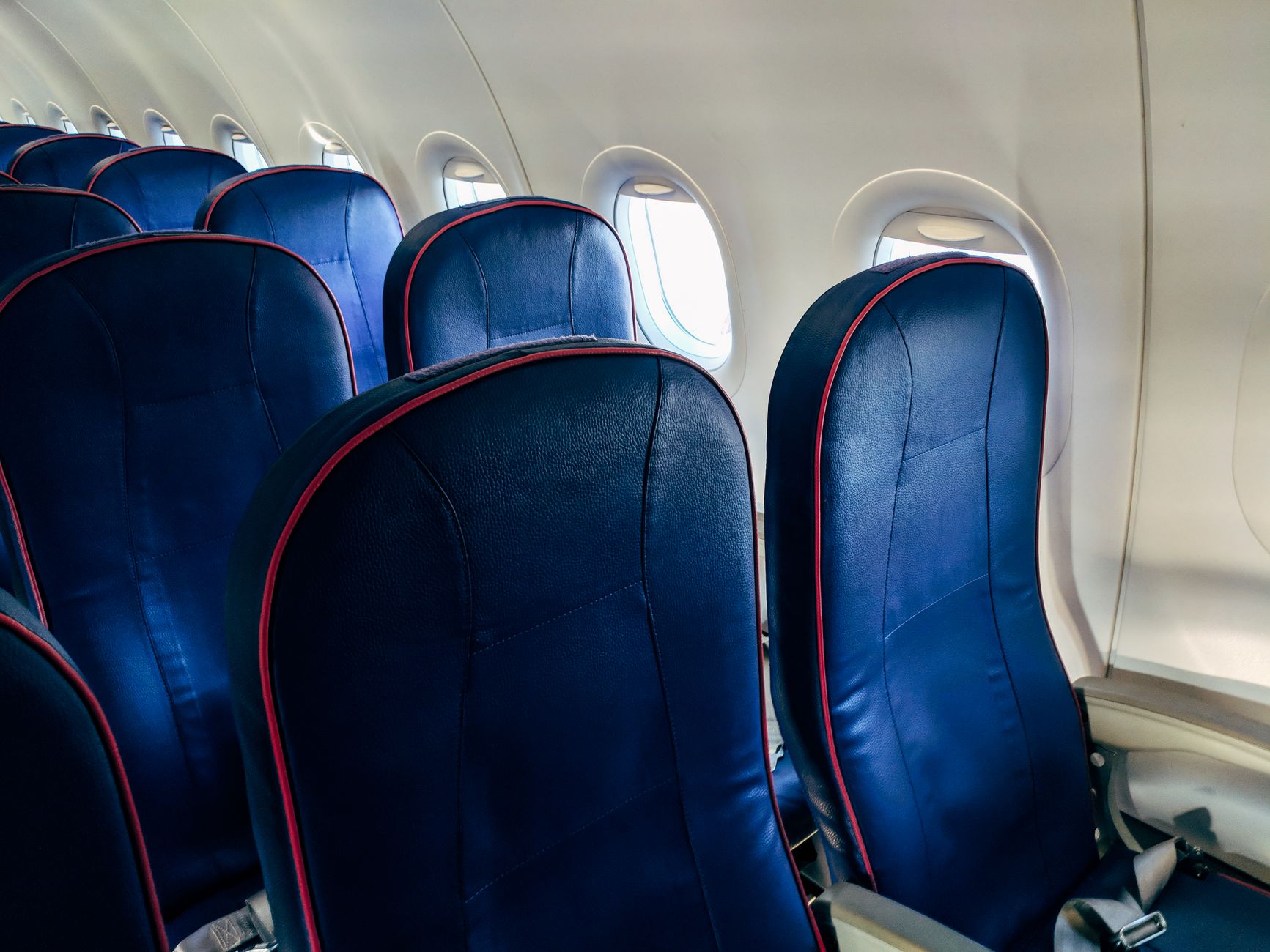 Close-up of empty airplane seats with windows showing daylight. Ideal for travel themes.
