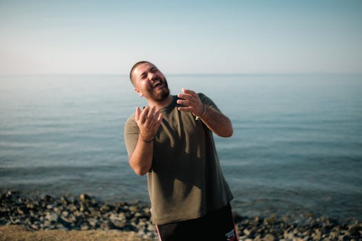 A man joyfully laughing against the serene seascape of İskenderun, Hatay, Türkiye.