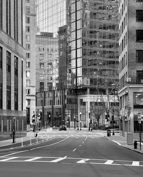 Free A monochrome urban scene of a deserted city street bordered by tall skyscrapers. Stock Photo