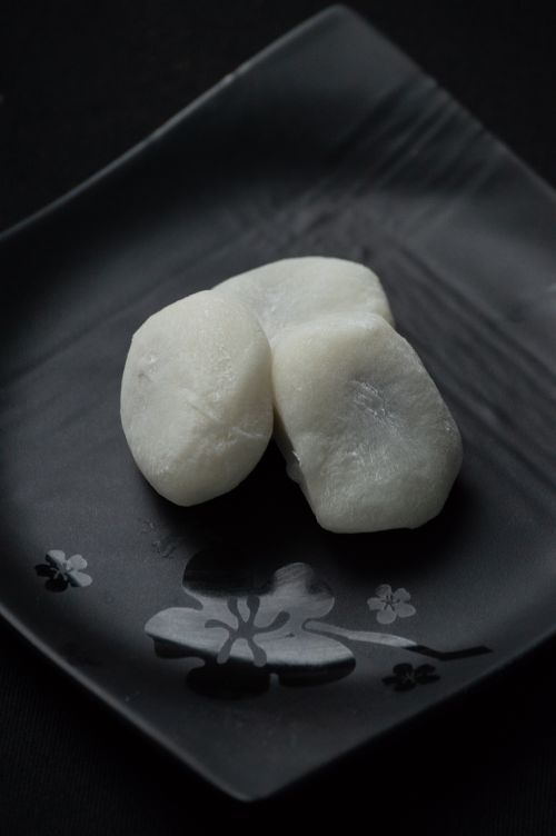 Free A close-up of traditional Japanese mochi rice cakes on a black ornamental plate. Stock Photo