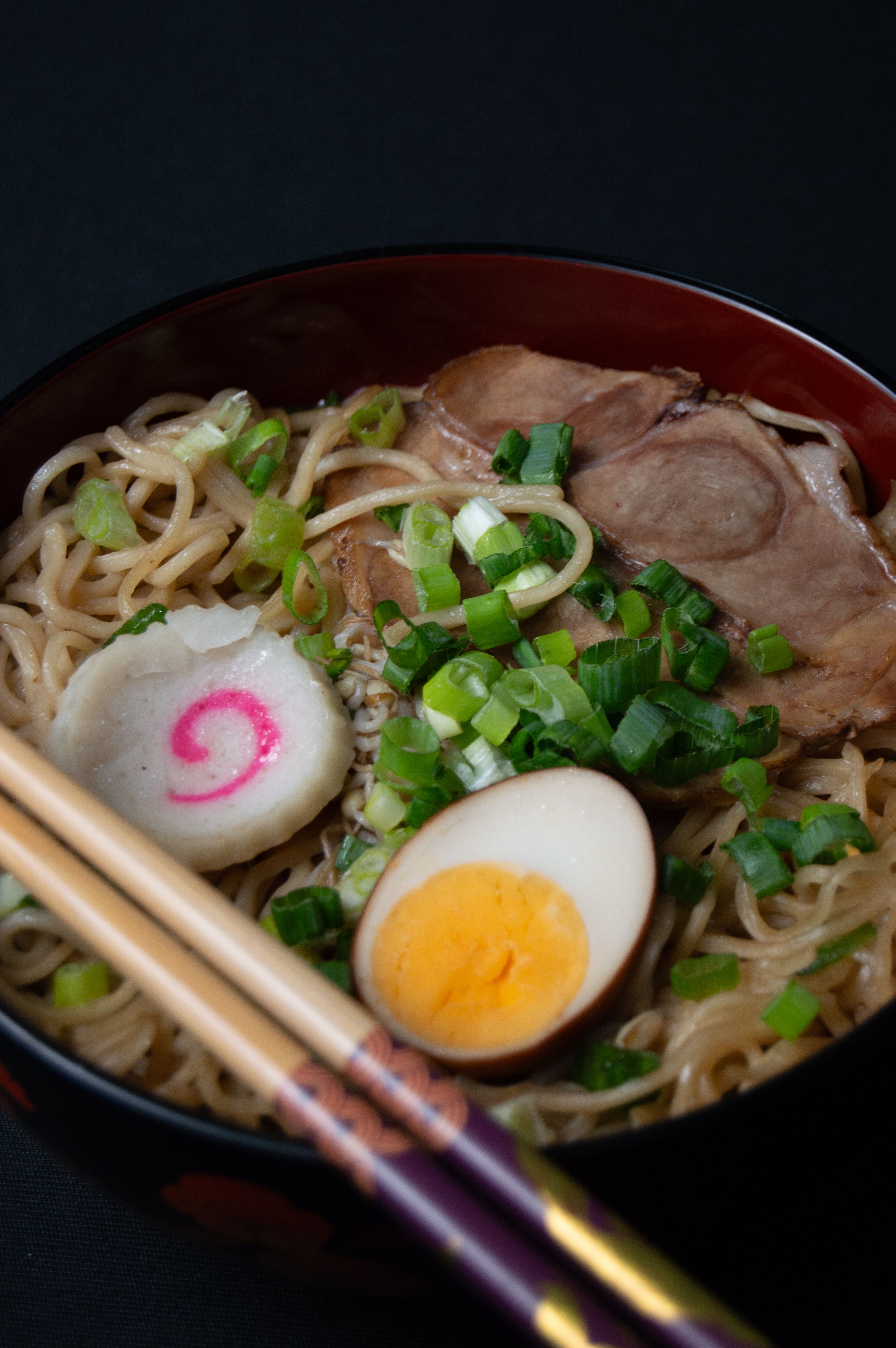 Close-up of ramen bowl with soft egg, narutomaki fish cake, and chashu pork