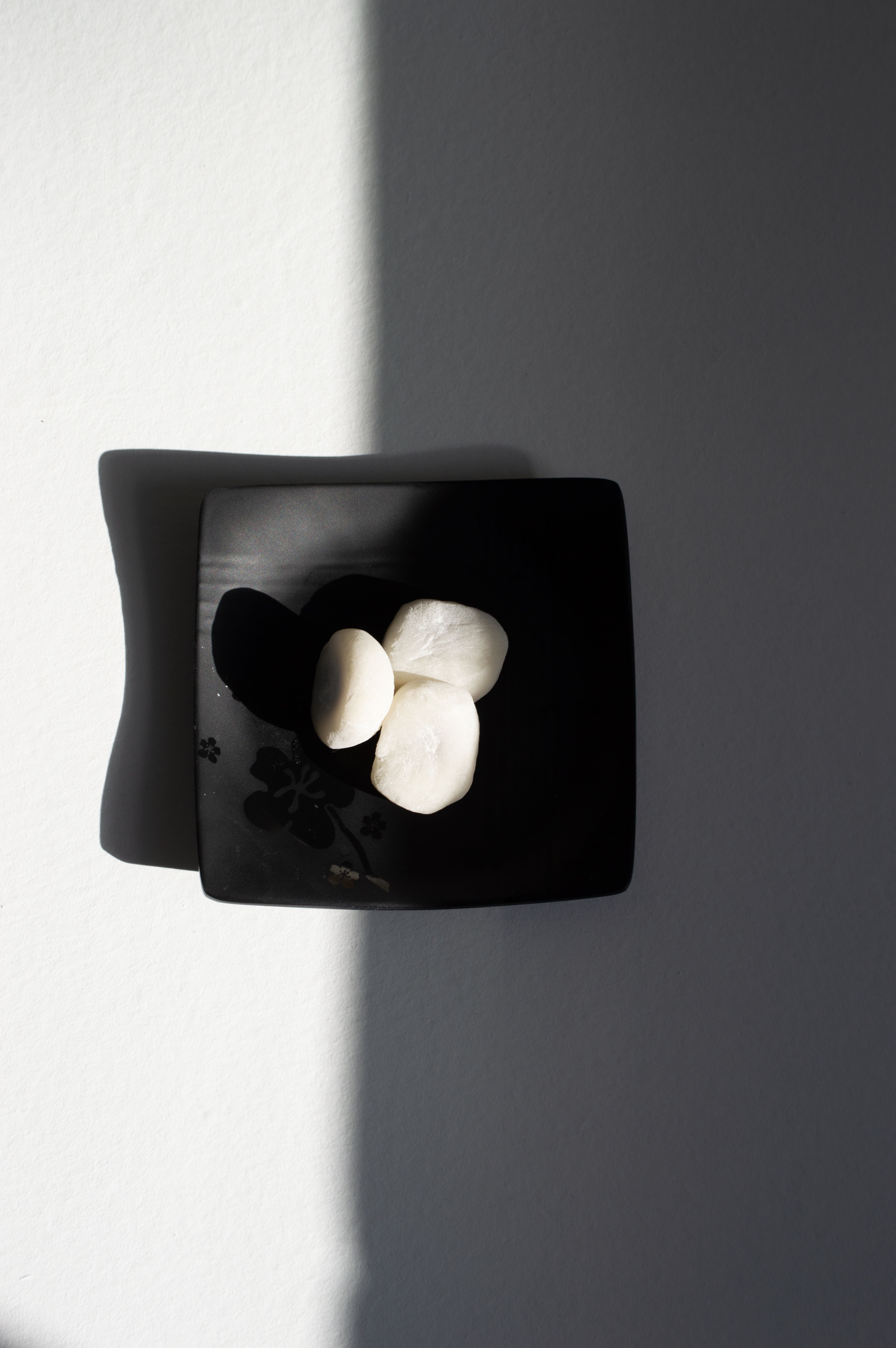 A minimalist black plate with scallops highlighted by natural light and shadows.