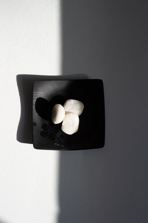 Free A minimalist black plate with scallops highlighted by natural light and shadows. Stock Photo