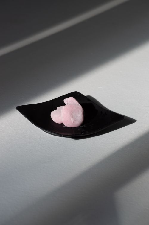 Free A minimalist display of a pink stone on a black plate, creating a soothing visual contrast with soft lighting. Stock Photo