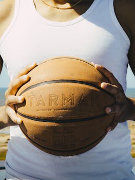 Person holding a basketball outside in Rabat, Morocco, under sunny conditions, symbolizing sports culture.