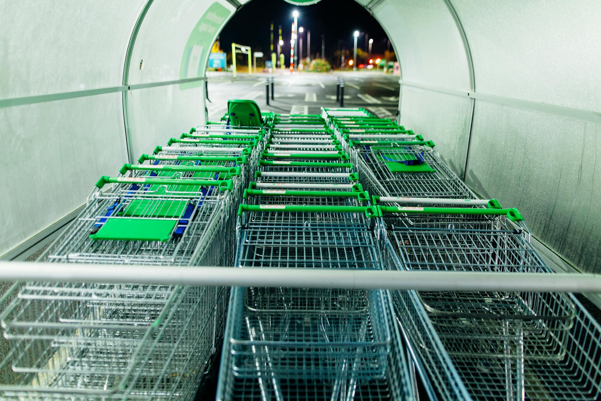 Multiple shopping carts lined up in an outdoor storage area during nighttime.