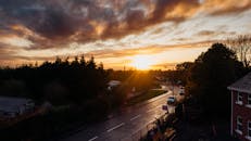 从树木和建筑环绕的安静城市街道望去，日落时分的优美风景被温暖的色调笼罩